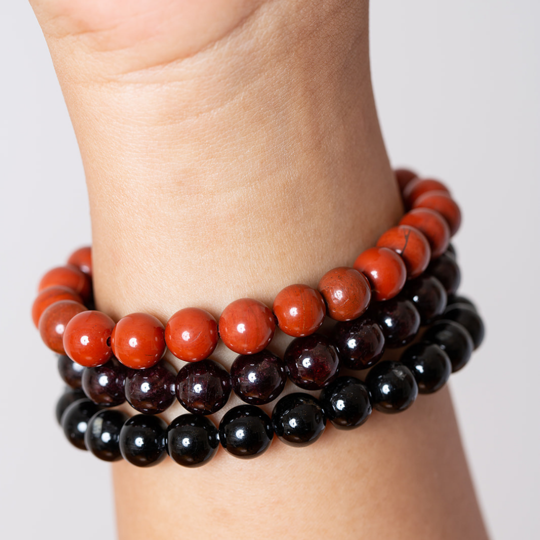 women's wrist with red jasper, garnet, and black tourmaline mala beads