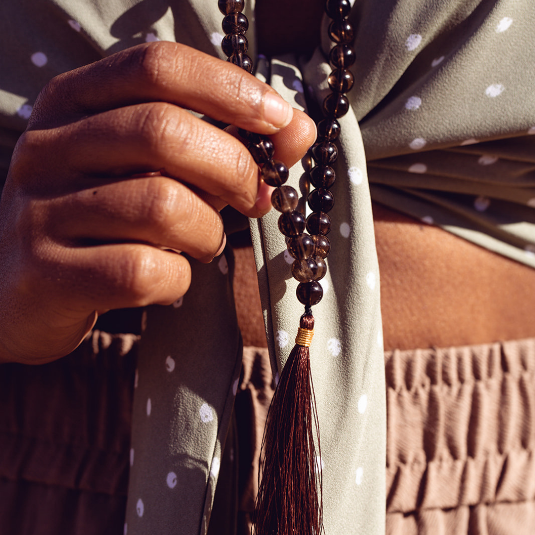 Close up of woman wearing and holding Ambarya Release - Smoky Quartz Mala Bead necklace
