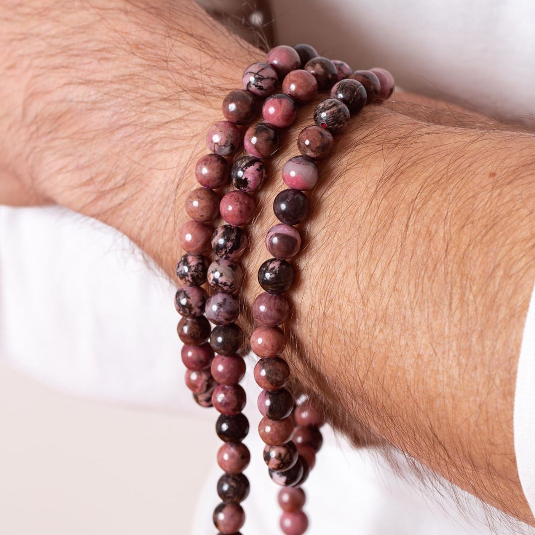 Close up of Man wearing Ambarya Emotional Balance - Rhodonite crystal Mala Bead necklace wrapped around his wrist