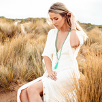 Woman looking down and sitting in long grass wearing Green Aventurine crystal Mala Bead Set