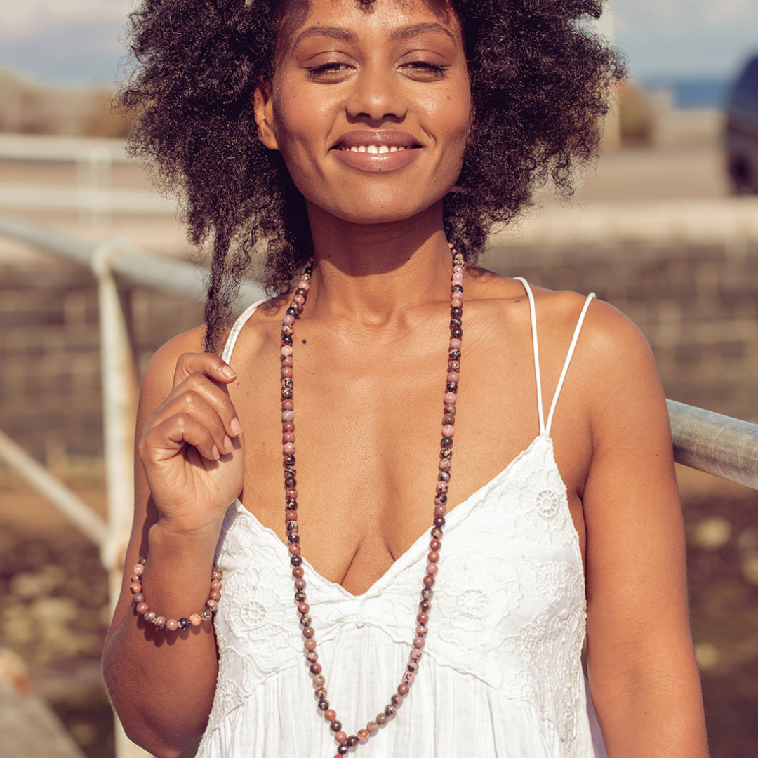 Woman smiling at the camera wearing Ambarya Emotional Balance - Rhondonite Mala Bead Set