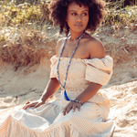 Woman looking to the side, sitting in the sand wearing Ambarya Insight - Sodalite Mala Bead Set