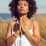 Woman outside in the sun. Standing with hands in prayer position she is wearing Ambarya Hope - Amazonite Mala Bead Set