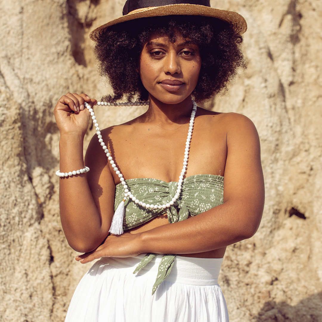 Woman smiling at the camera she is wearing Ambarya Patience - Howlite Mala Bead Set. 