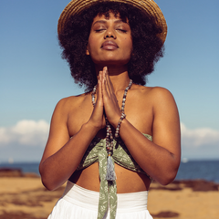Woman with eyes closed and hands in prayer position she is wearing Ambarya Acceptance - Botswana Agate Mala Bead Set